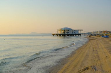 İtalya 'nın Senigallia şehrinde gün doğumunda gökyüzü, deniz ve kıyı şeridi boyunca rotonda al mare. Kartpostal Modern mimari