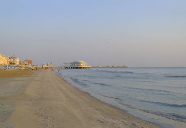 İtalya 'nın Senigallia şehrinde gün doğumunda gökyüzü, deniz ve kıyı şeridi boyunca rotonda al mare. Kartpostal Modern mimari