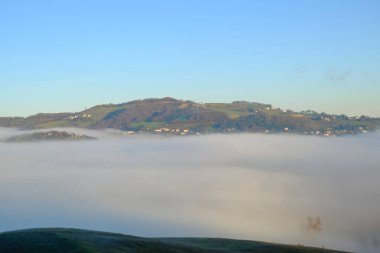 fog over the mountains and hills across the blue sky. Natural foggy landscape. Minimalistic panorama