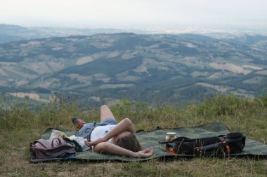 Girl lying on the blanket across the mountains landscape. Camping in the mountains, hiking, trekking, travel