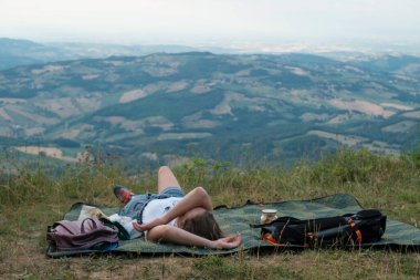 Girl camping in the mountains. Young woman  lying on the blanket across the mountain view