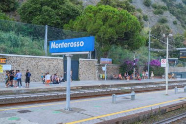 Haziran 2023 Monterosso, İtalya: Trenler, istasyon altyapısı ve bavullu yolcular arasındaki demiryolu platformunda Monterosso imzası