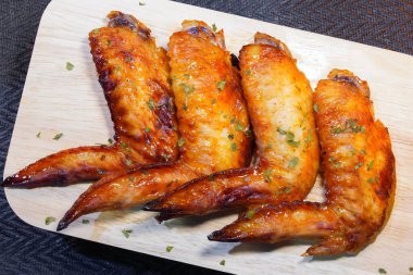 Bir ahşap tahta üzerinde ızgara tavuk kanadı.