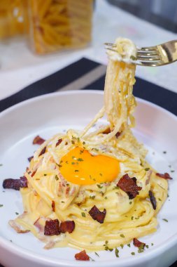 Üstünde yumurta, parmesan peyniri, krem sosu ve pastırma olan Carbonara makarnası. Geleneksel İtalyan mutfağı