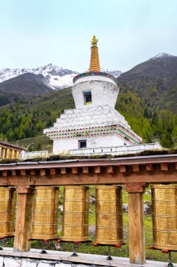 Beyaz stpa ile tibet dua tekerlekleri ve arka planda kar dağ