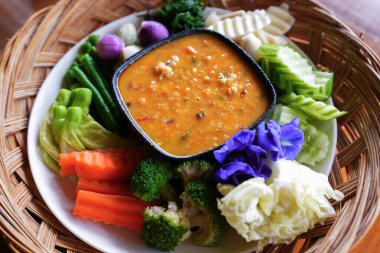 Bir el biber ezmesini taze sebzeye batırıyor.