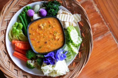 Bir el biber ezmesini taze sebzeye batırıyor.