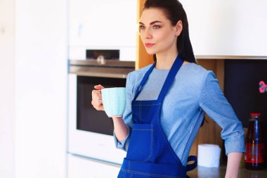 Mutfak arka planında fincanı olan genç bir kadının portresi..