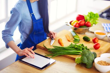 Mutfakta sebze doğrayan genç bir kadın..