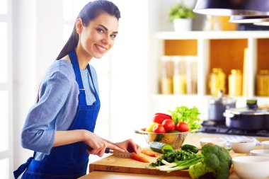 Mutfakta sebze doğrayan genç bir kadın..