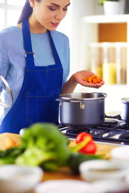 Mutfakta ahşap kaşıkla yemek pişiren kadın.