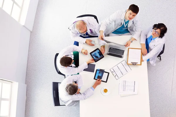 Medical team sitting and discussing at table, top view.