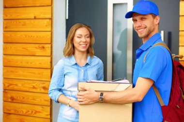 Mavi üniformalı gülümseyen kurye servis konseptine paket kutusu teslim eden teslimatçı. Mavi üniformalı gülümseyen teslimatçı..