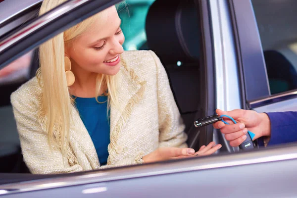 一个漂亮的年轻女子坐在一家经销商的新车里 正笑着拿钥匙 — 图库照片