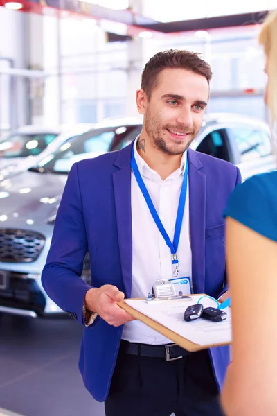 車の販売員は車の販売代理店で幸せな顧客に車を販売し キーの上に手 — ストック写真