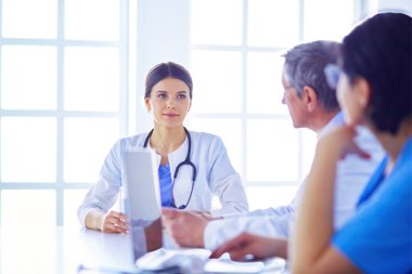 Ciddi bir tıbbi ekip parlak bir ofiste dizüstü bilgisayar kullanıyor.