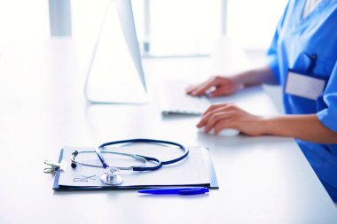 Kadın doktor masada oturuyor ve hastanede dizüstü bilgisayarla çalışıyor..