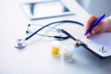 Elinde bir kutu beyaz hap ve masada yazılı tedavi planı tutan bir kadın..