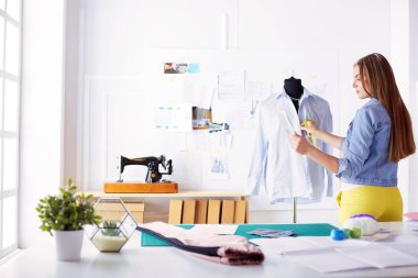 Çekici genç kadın yeni giysi koleksiyonu oluşturma sürecinde.