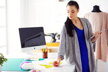 Güzel genç bir kadın dijital tablet üzerinde çalışıyor ve çalışırken gülümsüyor..