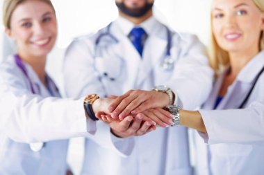 Doktorlar ve hemşireler tıbbi bir ekipte el ele tutuşuyorlar..