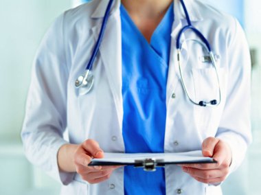 Üniformalı bir dosyayla gülümseyen kadın doktor.