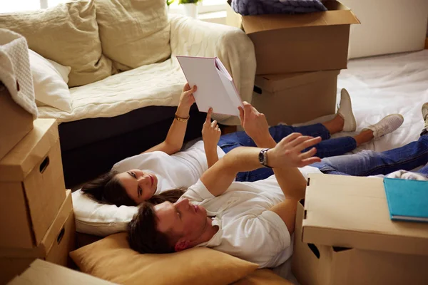 他们的新房子中的文本框 在打开包装后躺在地上的年轻夫妇 — 图库照片