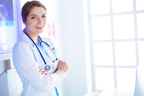 穿着白色制服站在诊所办公室的年轻女医生 — 图库照片