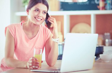 Mutfakta dizüstü bilgisayara benzeyen tariflerle gülümseyen genç bir kadın. Gıda blogcusu kavramı.