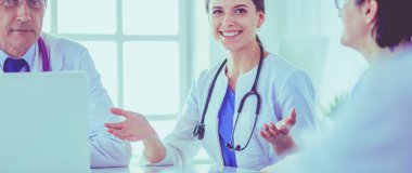 Ciddi bir tıbbi ekip parlak bir ofiste dizüstü bilgisayar kullanıyor.