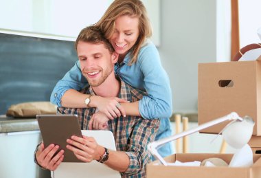 Genç bir çift yeni ev içinde hareket. Oturma ve açma sonra rahatlatıcı. Bir şey üstünde laptop arıyorum. Genç Çift.