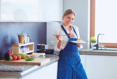 Mutfakta sobanın yanında duran genç bir kadın..