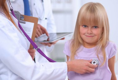 Kadın doktor, ameliyatta steteskoplu çocuğu muayene ediyor.