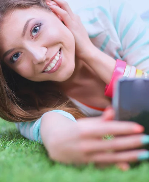 Güzel Genç Bir Kadın Yeşil Çimenlerde Yatarken Telefonuyla Selfie Çekiyor — Stok fotoğraf