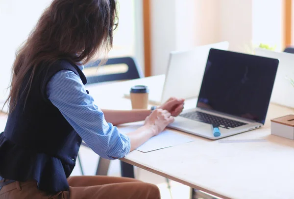若い女性がノートパソコンを持ってオフィスのテーブルに座っている 若い女性だ ノートパソコン — ストック写真