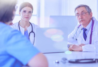 Ciddi bir tıbbi ekip parlak bir ofiste dizüstü bilgisayar kullanıyor.