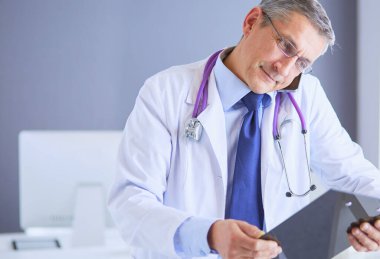 Erkek doktor hastanedeki panoya notlar yazıyor..