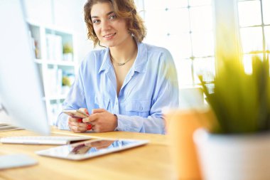 Evdeki bir masada birden fazla cihaz kullanarak çalışan mutlu kadın..