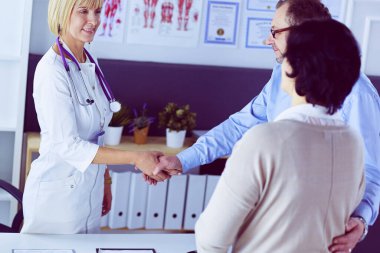 Kadın doktor bir hastanın elini sıkıyor ve gülümsüyor..