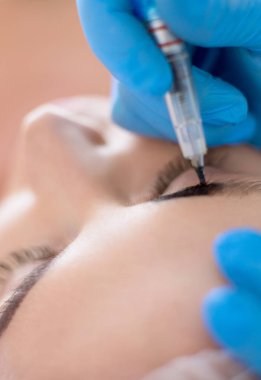 Kaşlar için kalıcı makyaj. Güzellik salonunda kalın kaşlı güzel bir kadın..