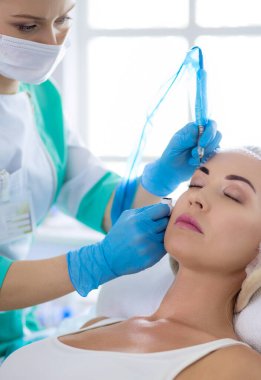 Kaşlar için kalıcı makyaj. Güzellik salonunda kalın kaşlı güzel bir kadın..