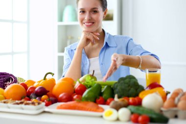 Ahşap iç kısımda meyve ve sebze dolu masada oturan genç ve tatlı bir kadın..