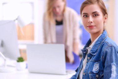 Masanın yanında duran iki genç kadın enstrüman, plan ve dizüstü bilgisayarla.