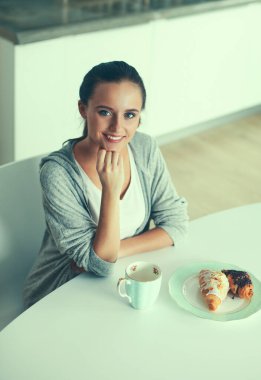 Mutfak masasında tatlı kruvasan ile çay içme kadın.
