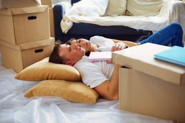 Bir sürü kutuyla yerde yatan mutlu çiftin yüksek görüntüsü.