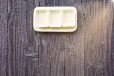 Ahşap masa zemininde kare şeklinde boş seramik tabaklar, üst görünüm.