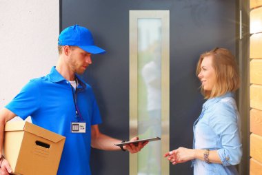 Mavi üniformalı gülümseyen kurye servis konseptine paket kutusu teslim eden teslimatçı. Mavi üniformalı gülümseyen teslimatçı..