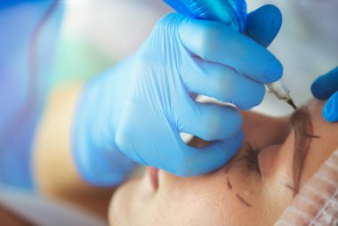 Kaşlar için kalıcı makyaj. Güzellik salonunda kalın kaşlı güzel bir kadın.