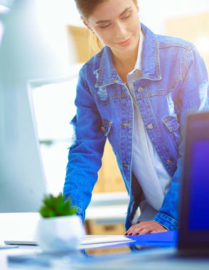 Masanın yanında duran iki genç kadın enstrüman, plan ve dizüstü bilgisayarla