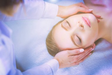 Masaj masasında uzanmış gözleri kapalı rahatlayan genç bir kadın. - Kadın. Spa salonu.